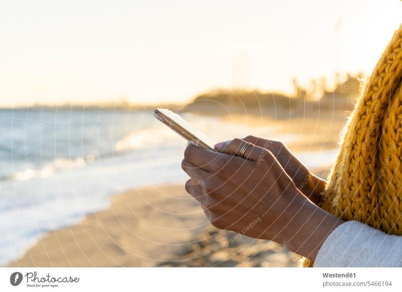 Frau mit gelbem Schal, mit Smartphone am Strand Schals iPhone Smartphones Nachricht Mitteilung Botschaft Frau mittleren Alters Frauen mittleren Alters gelber
