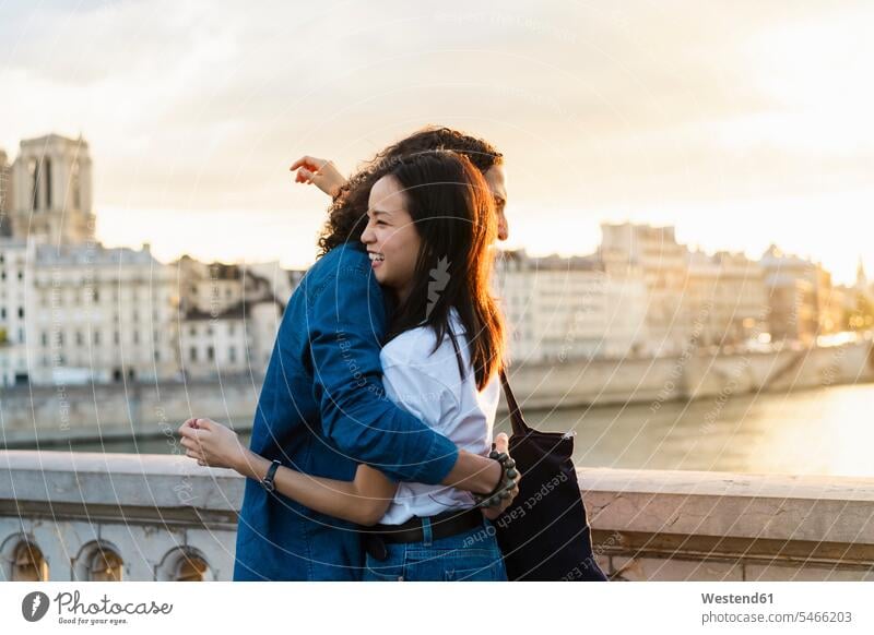 Frankreich, Paris, glückliches junges Paar umarmt sich bei Sonnenuntergang an der Seine Glück glücklich sein glücklichsein Sonnenuntergänge Pärchen Paare