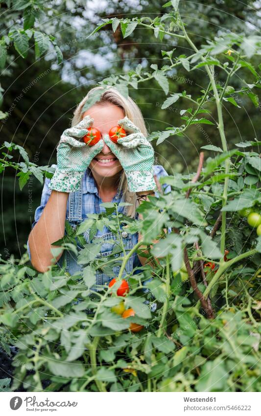 Blond lächelnde Frau bei der Tomatenernte, Tomaten auf Augen freuen Glück glücklich sein glücklichsein zufrieden rote roter rotes blinde blinder blindes