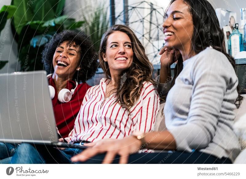 Drei glückliche Frauen mit Laptop sitzen auf Couch Notebook Laptops Notebooks sitzend sitzt weiblich Glück glücklich sein glücklichsein Sofa Couches Liege Sofas