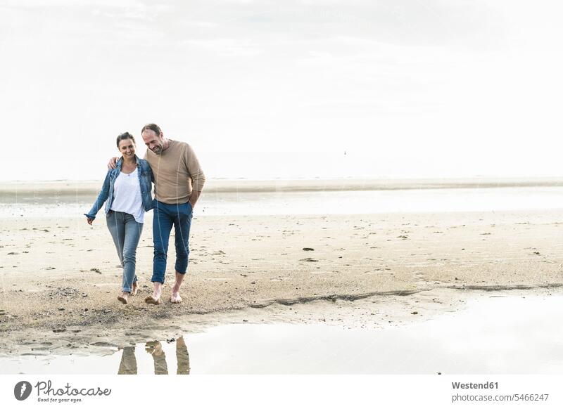 Lächelndes reifes Paar, das bei Sonnenuntergang am Strand gegen den Himmel läuft Farbaufnahme Farbe Farbfoto Farbphoto Niederlande Holland Freizeitbeschäftigung