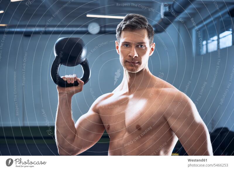 Athletischer Mann ohne Hemd posiert mit Kesselglocke im Fitnessstudio sportlich Pose posieren Rundgewicht Kettlebell Kugelhantel Kettlebells Workout