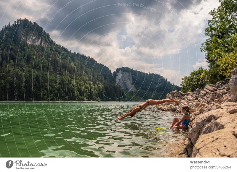 Österreich, Salzkammergut, Mondsee, Frau mit Tochter springt in See Seen springen hüpfen Gewässer Wasser Sprung Spruenge Sprünge Erfrischung erfrischen