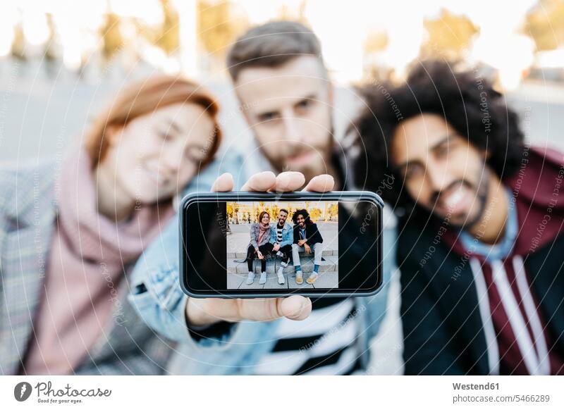 Drei Freunde zeigen ein Selfie auf einem Fotohandy vorführen präsentieren Vorführung herzeigen Fotohandys Kamera-Handy Kamerahandys Kamera-Handys Selfies