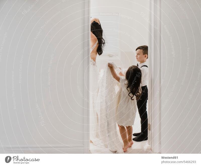 Tochter hält Kleid in der Hand, während der Sohn die Mutter ansieht, die sich im Badezimmer für die Hochzeit fertig macht Farbaufnahme Farbe Farbfoto Farbphoto