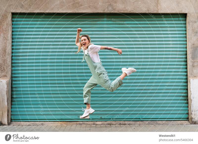 Glückliche junge Frau springt vor Freude in der Stadt springen Spruenge Sprünge hüpfen freuen Frohsinn Fröhlichkeit Heiterkeit glücklich sein glücklichsein