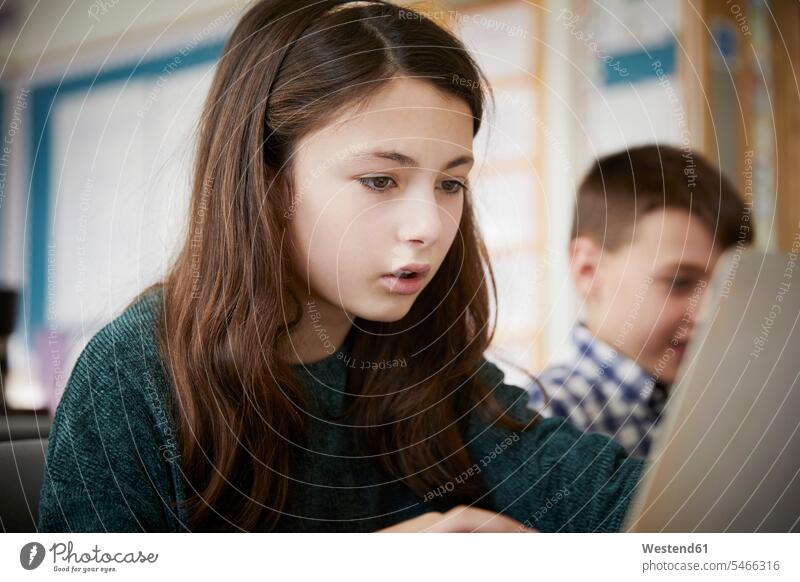 Mädchen und Junge in einem Klassenzimmer während einer Unterrichtsstunde über Laptops Ausbildung Schueler Schulkinder Schüler Rechner Notebook Notebooks Arbeit