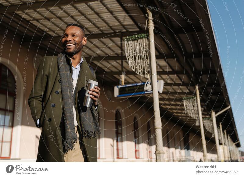 Glücklicher stilvoller Mann mit wiederverwendbarem Becher wartet auf den Zug geschäftlich Geschäftsleben Geschäftswelt Geschäftsperson Geschäftspersonen