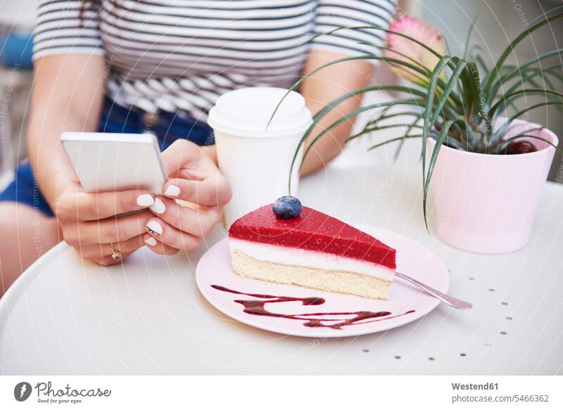 Nahaufnahme einer Frau, die ein Mobiltelefon benutzt und Kuchen in einem Café isst essen essend weiblich Frauen Handy Handies Handys Mobiltelefone Cafe