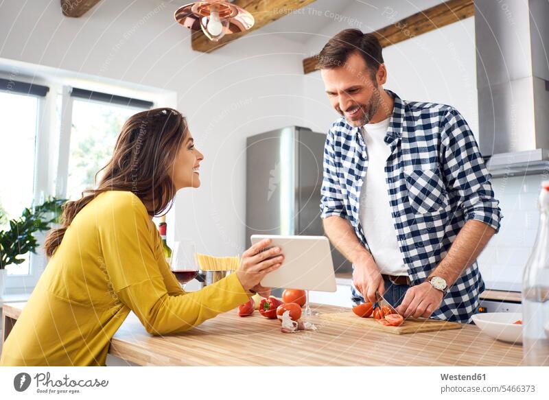 Zärtliches Paar in der Küche, das gemeinsam Spaghetti zubereitet und ein digitales Tablet benutzt zubereiten kochen Essen zubereiten Küchen Gemeinsam Zusammen
