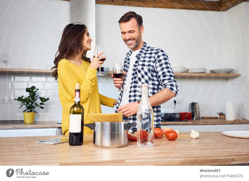 Zärtliches Paar in der Küche, bereitet gemeinsam Spaghetti zu, trinkt roten Wein Rotwein Rotweine kochen lächeln Pärchen Paare Partnerschaft trinken liebevoll