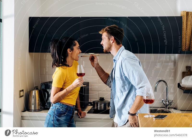 Glückliches junges Paar kocht und trinkt gemeinsam Wein in der heimischen Küche Gläser Trinkglas Trinkgläser Weingläser Kochtoepfe Kochtöpfe Topf Töpfe