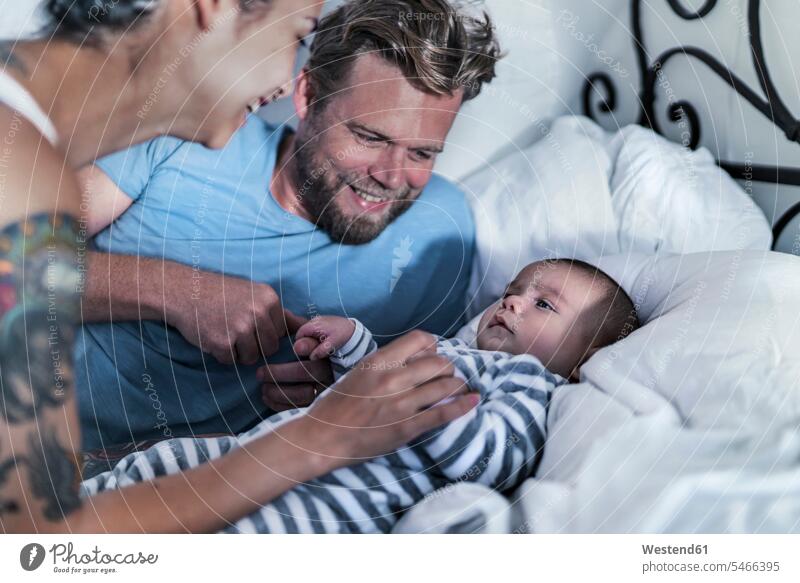 Glückliche Eltern mit ihrem Baby im Bett Leute Menschen People Person Personen Europäisch Kaukasier kaukasisch gemischtrassig Gruppe von Menschen Menschengruppe