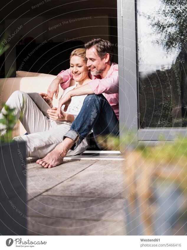 Reifes Paar entspannt sich gemeinsam an offener Terrassentür mit Tablette Entspannung relaxen entspannen Terrassentuer Pärchen Paare Partnerschaft benutzen