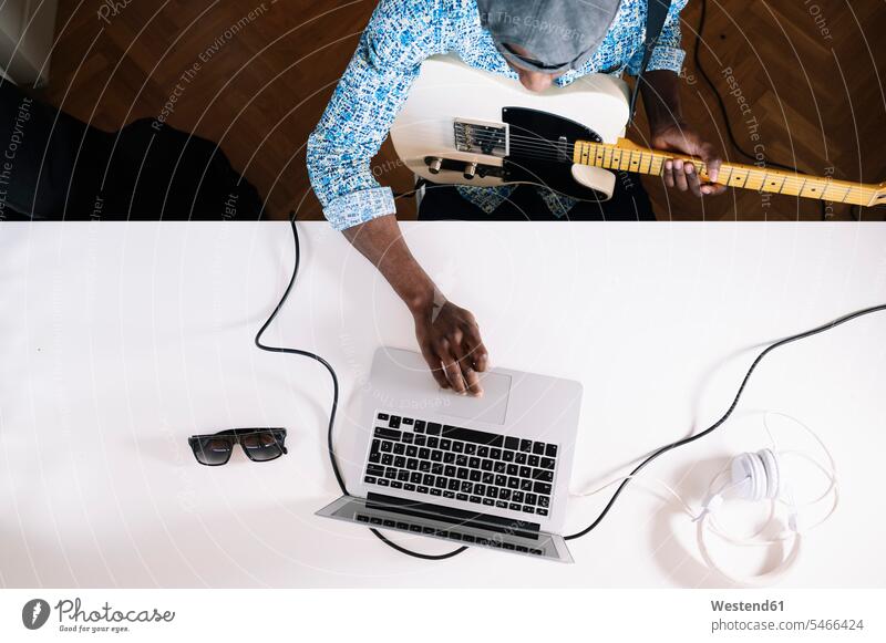Junger Mann lernt zu Hause über das Internet Gitarre spielen Farbaufnahme Farbe Farbfoto Farbphoto Innenaufnahme Innenaufnahmen innen drinnen Spanien