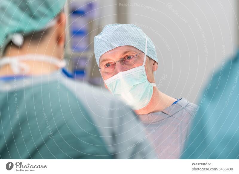 Chirurg während der Operation, Blick zum Kollegen Arbeitskollege Arbeitskollegen Job Berufe Berufstätigkeit Beschäftigung Jobs Brillen Gesundheit