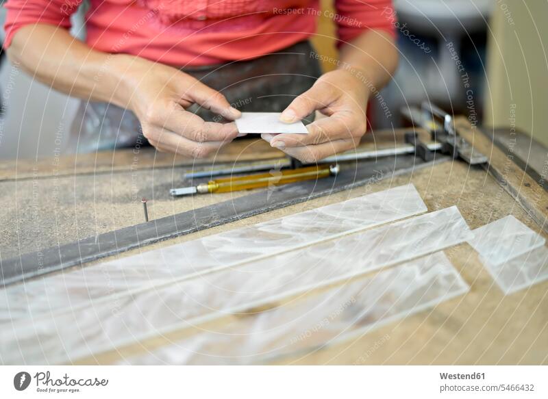 Nahaufnahme einer Frau, die in einer Glaserwerkstatt an einem Glasstück arbeitet Stück Stueck Stücke Stuecke Glaserei Glasereien arbeiten Arbeit Werkstatt