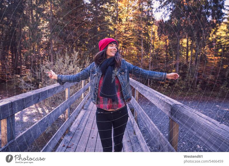 Frau mit rotem Wollhut und Jeansjacke auf einer Brücke im Herbst Leute Menschen People Person Personen Europäisch Kaukasier kaukasisch 1 Ein ein Mensch