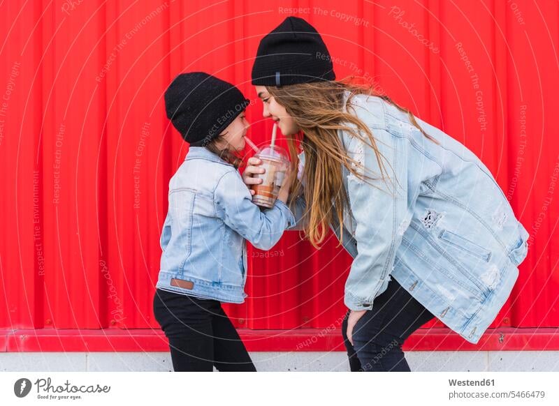 Teenager-Mädchen und kleine Schwester haben Spaß zusammen Spanien Jeansjacke Jeansjacken Wollmütze Wollmützen Strickmütze Strickmützen wehende Haare