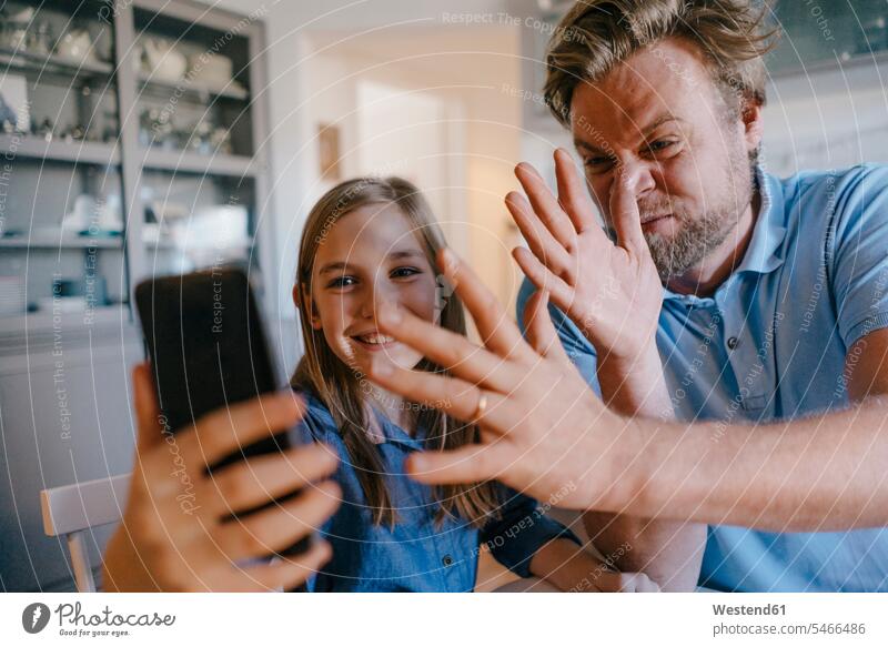 Verspielter Vater und Tochter machen ein Selfie zu Hause sitzen sitzend sitzt Gemeinsam Zusammen Miteinander Handzeichen Zeichen Zuhause daheim Hände positiv