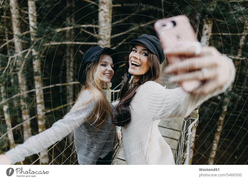 Zwei glückliche junge Frauen auf einer Hängebrücke machen ein Selfie Glück glücklich sein glücklichsein Haengebruecke Hängebrücken Haengebruecken weiblich