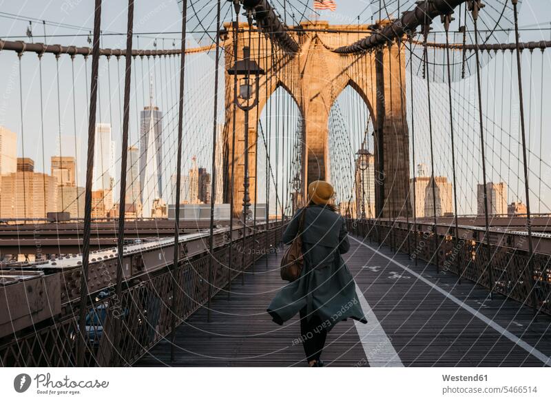 USA, New York, New York City, weiblicher Tourist auf Brooklyn Bridge im Morgenlicht gehen gehend geht Touristin morgendliches Licht Frau Frauen Reisende