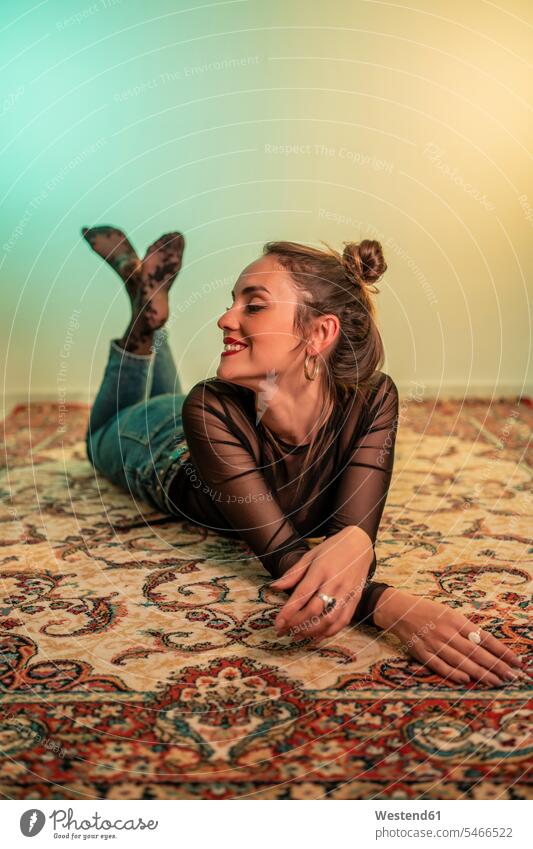 Porträt einer lächelnden jungen Frau auf einem Teppich liegend Teppiche freuen Glück glücklich sein glücklichsein Lifestyles Attraktivität gut aussehend