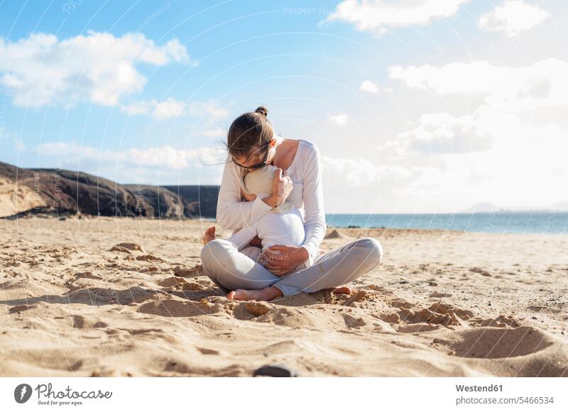 Mutter kuschelt mit kleiner Tochter am Strand Beach Straende Strände Beaches glücklich Glück glücklich sein glücklichsein Baby Babies Babys Säuglinge Kind