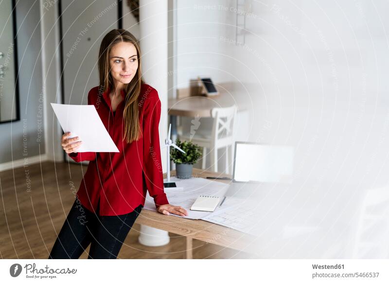 Frau im Büro hält Papier mit Windrad-Modell auf dem Tisch Job Berufe Berufstätigkeit Beschäftigung Jobs geschäftlich Geschäftsleben Geschäftswelt