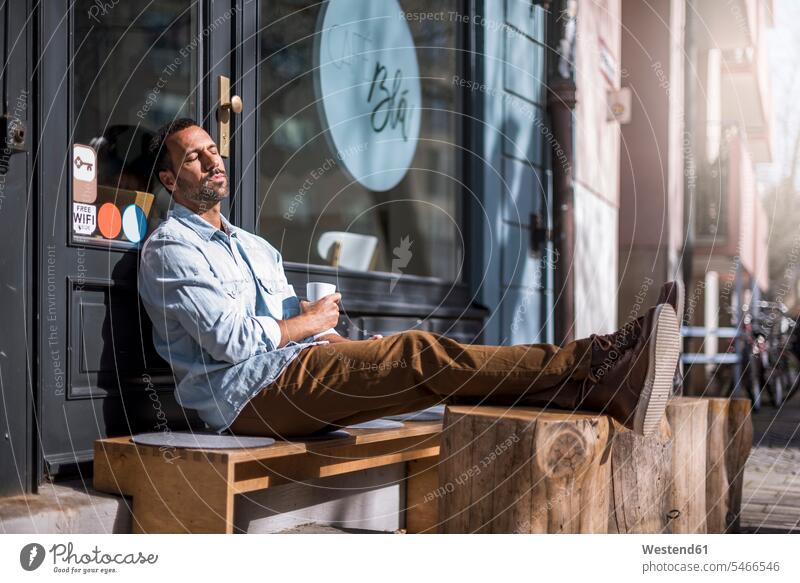 Entspannter Mann sitzt vor einem Café und genießt den Sonnenschein genießen geniessen Genuss sitzen sitzend Männer männlich Cafe Kaffeehaus Bistro Cafes Cafés