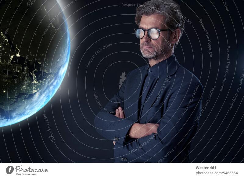 Porträt eines reifen Geschäftsmannes vor dunklem Hintergrund beim Beobachten des schwebenden Planeten Erde geschäftlich Geschäftsleben Geschäftswelt