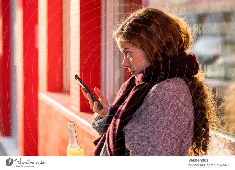 Teenager-Mädchen liest SMS, hält Flasche mit einem Getränk hübsch Teenagerin junges Mädchen Teenagerinnen weiblich junge Frau Smartphone iPhone Smartphones