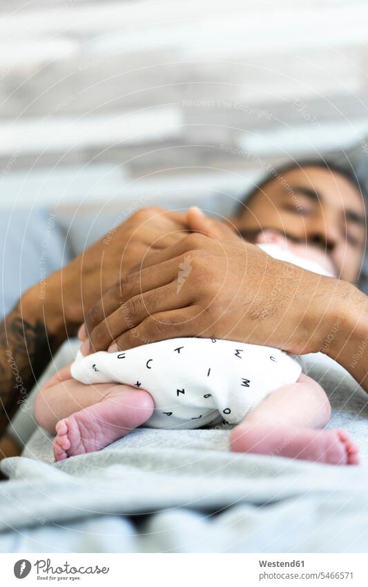 Mann schlafend im Bett hält sein neugeborenes Baby ausruhen Rast Erholung erholen Babies Babys Säuglinge Kind Kinder Unschuld Schuldlosigkeit schuldlos