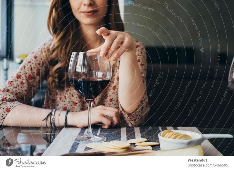 Junge Frau berührt Weinglas, während sie am Esstisch sitzt Farbaufnahme Farbe Farbfoto Farbphoto Innenaufnahme Innenaufnahmen innen drinnen