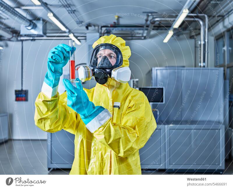 Chemikerin bei der Arbeit im Industrielabor, Kontrolle des Reagenzglases Chemikanten arbeiten Schutzanzug Schutzanzuege Schutzanzüge Chemielabor