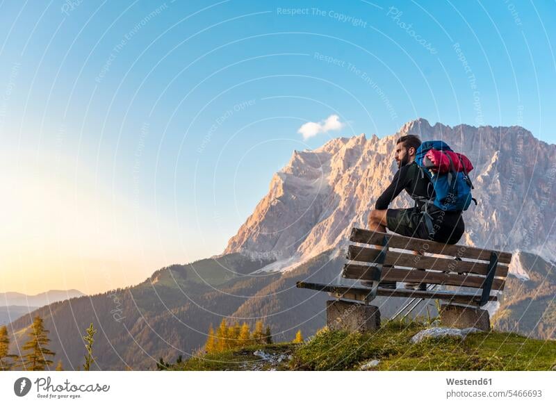 Österreich, Tirol, Wanderer in der Pause, auf der Bank sitzend, auf die Aussicht schauend Pause machen Holzbank Holzbänke Holzbaenke Sonnenuntergang