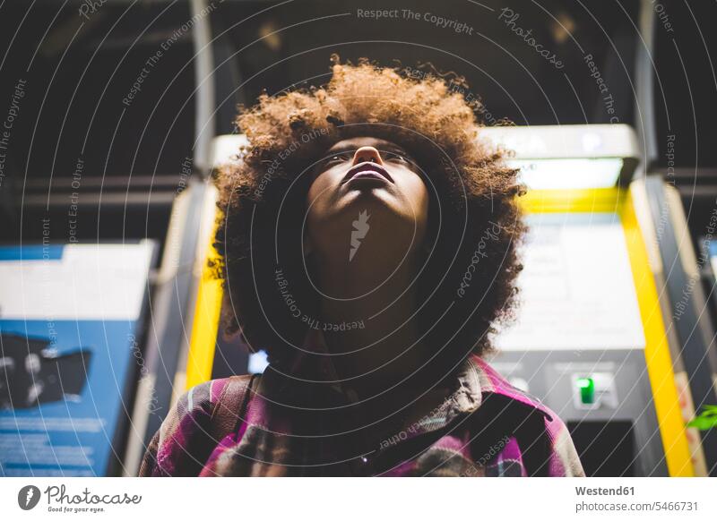 Junge Frau mit Afro-Frisur nachts am Fahrkartenautomaten aufblickend Leute Menschen People Person Personen gelockt gelockte Haare gelocktes Haar lockig