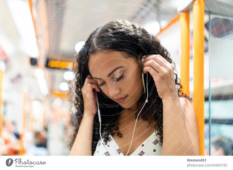 Junge Frau hört Musik mit Kopfhörern in der U-Bahn Ohrhörer In-Ear weiblich Frauen schön Ubahn U-Bahnen Untergrundbahnen Ubahnen Underground Subway hören hoeren