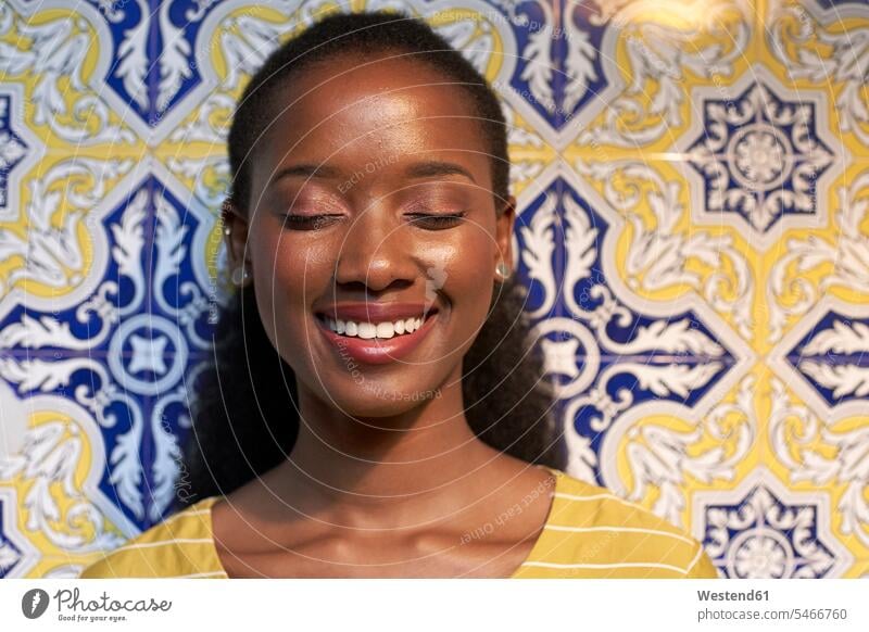 Porträt einer glücklichen jungen Frau an einer Kachelwand Schwarzer Afrikanisch Farbige Afrikanische Abstammung dunkelhäutig Farbiger Vorderansicht frontal