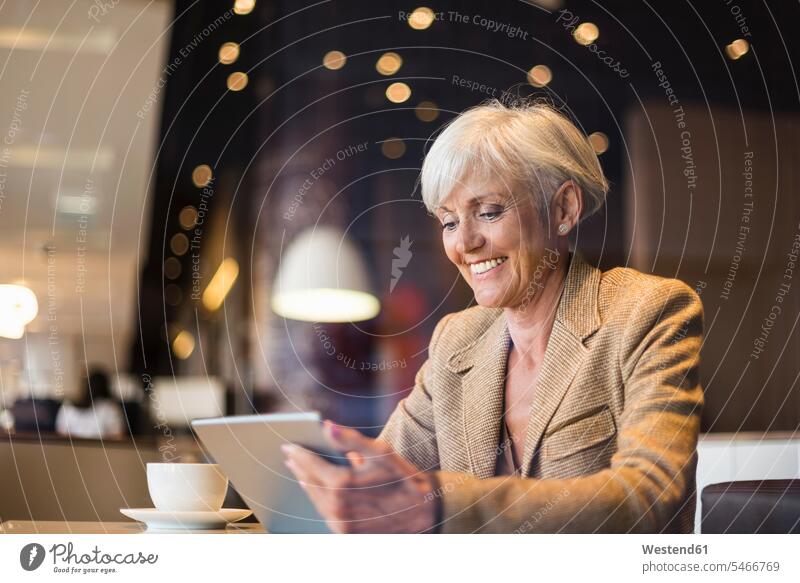 Lächelnde ältere Geschäftsfrau mit Tablet in einem Café Geschäftsfrauen Businesswomen Businessfrauen Businesswoman Frau weiblich Frauen Tablet Computer