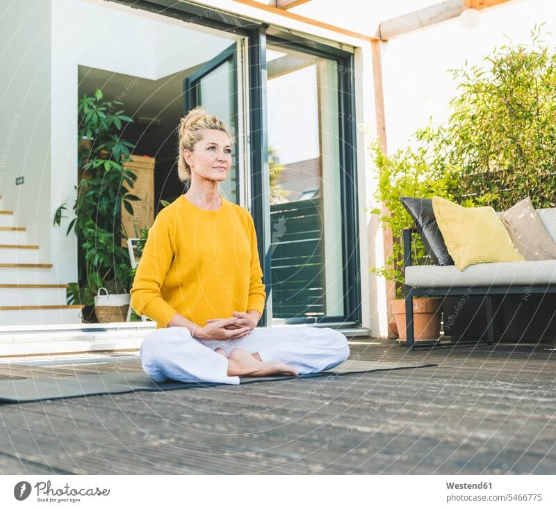 Porträt einer reifen Frau bei der Meditation auf der Terrasse entspannen relaxen sitzend sitzt Farben Farbtoene Farbton Farbtöne gelbe gelber gelbes daheim