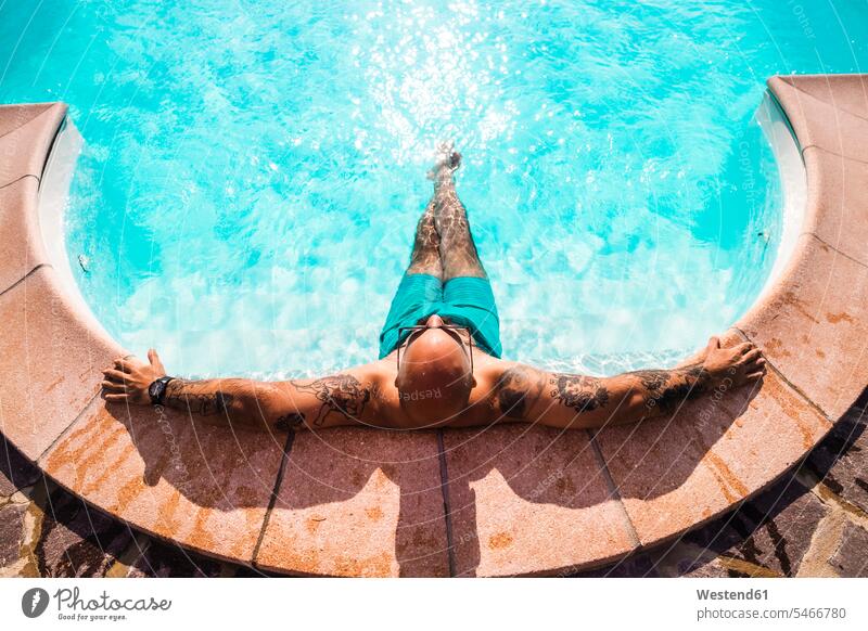 Mann entspannt sich an einem sonnigen Tag im Schwimmbad Farbaufnahme Farbe Farbfoto Farbphoto Außenaufnahme außen draußen im Freien Tageslichtaufnahme