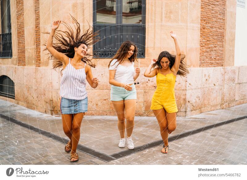 Drei unbekümmerte Freundinnen in der Stadt Freunde Kameradschaft dunkle Haare braunes Haar braunhaarig brünett gehend geht Jahreszeiten sommerlich Sommerzeit