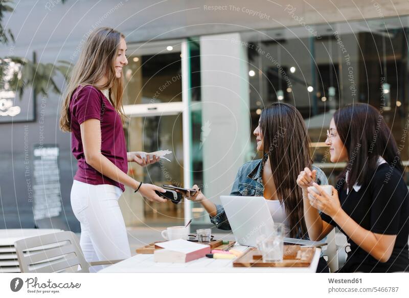 Junge Frau zahlt bargeldlos mit Smartphone in einem Café Spanien Kartenlesegerät Kartenlesegeraet Drahtlose Technologie drahtlose Verbindung