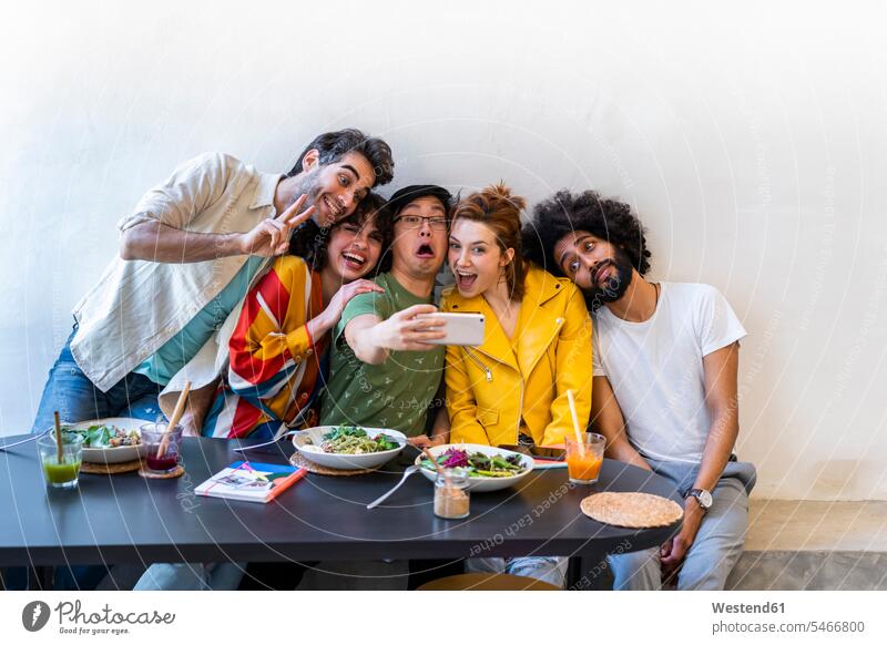 Gruppe von Freunden beim Mittagessen in einem Restaurant, die ein Selfie machen Gläser Trinkglas Trinkgläser Bilder Bildnis Fotos Tische Fotokamera Kamera