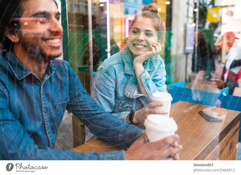 Porträt einer lächelnden jungen Frau in einem Café, die einen jungen Mann ansieht Fensterscheiben Flirt Muße Miteinander Zusammen Lifestyles Begegnung Bindung