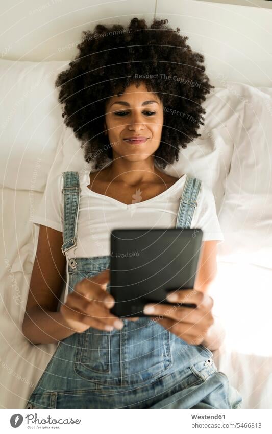 Lächelnde Frau liegt im Bett und liest ein E-Book Betten weiblich Frauen liegen liegend eBook lächeln lesen Lektüre Erwachsener erwachsen Mensch Menschen Leute