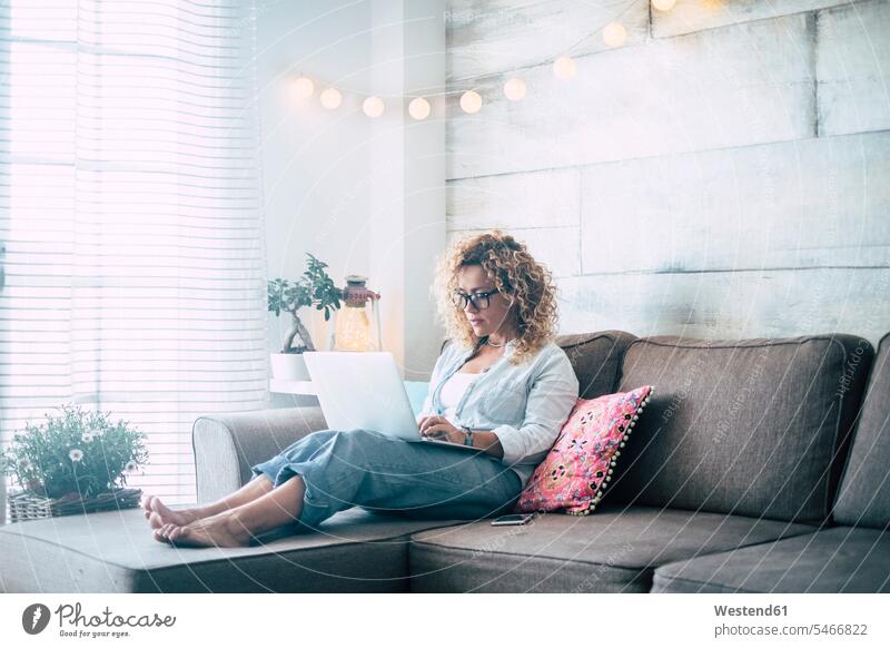 Frau mit Laptop auf der Couch zu Hause Freiberufler freiberuflich freie Berufe Mobilität mobil Locken lockiges Haar gelockte Haare gelocktes Haar Verbindung