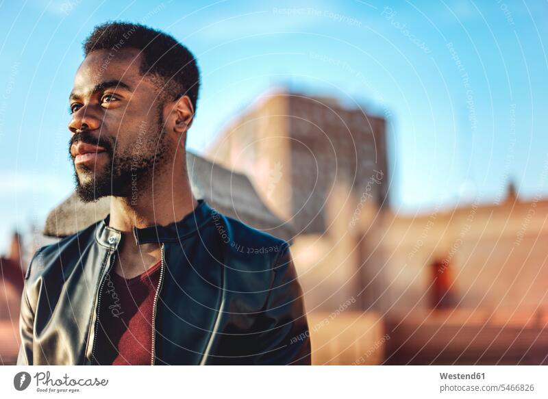Nahaufnahme eines nachdenklichen jungen Mannes in Lederjacke auf dem Dach einer Stadt Farbaufnahme Farbe Farbfoto Farbphoto Spanien Freizeitbeschäftigung Muße