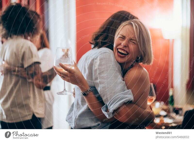 Glückliche junge Frau umarmt männlichen Freund während der Party zu Hause Farbaufnahme Farbe Farbfoto Farbphoto Innenaufnahme Innenaufnahmen innen drinnen
